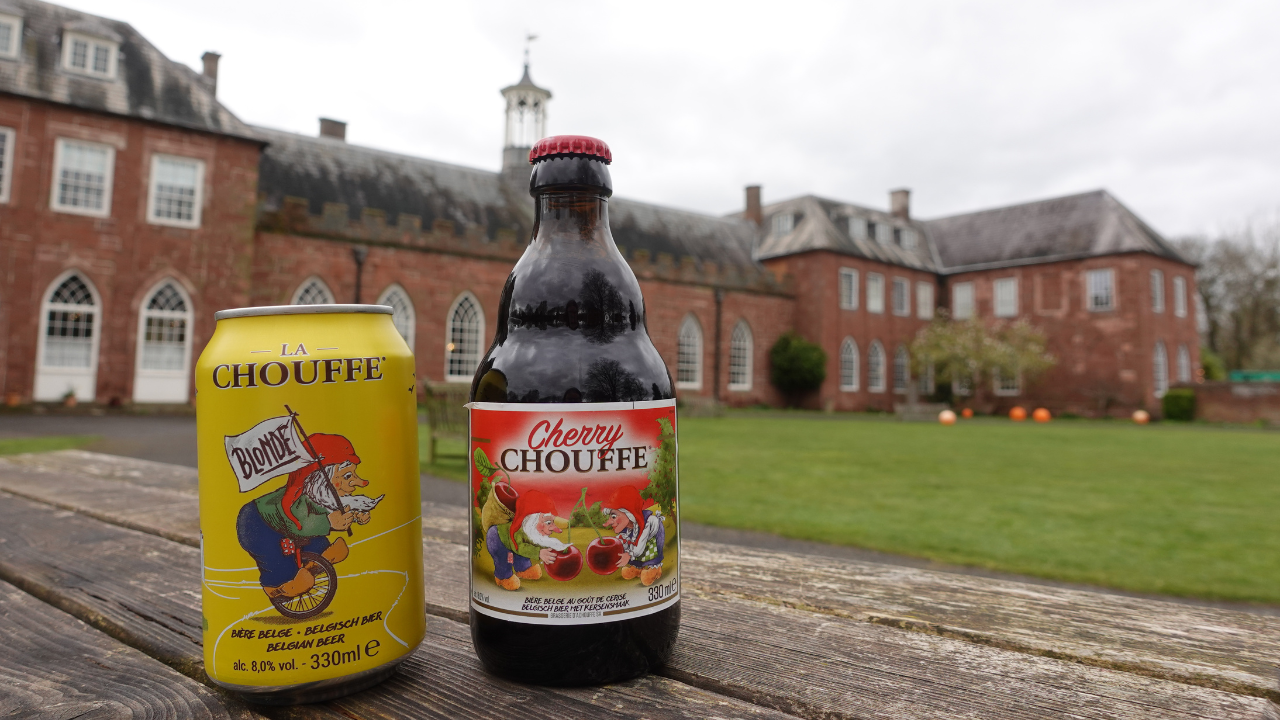 A can and a bottle of Chouffe Belgian beer in front of the Hartlebury Castle exterior