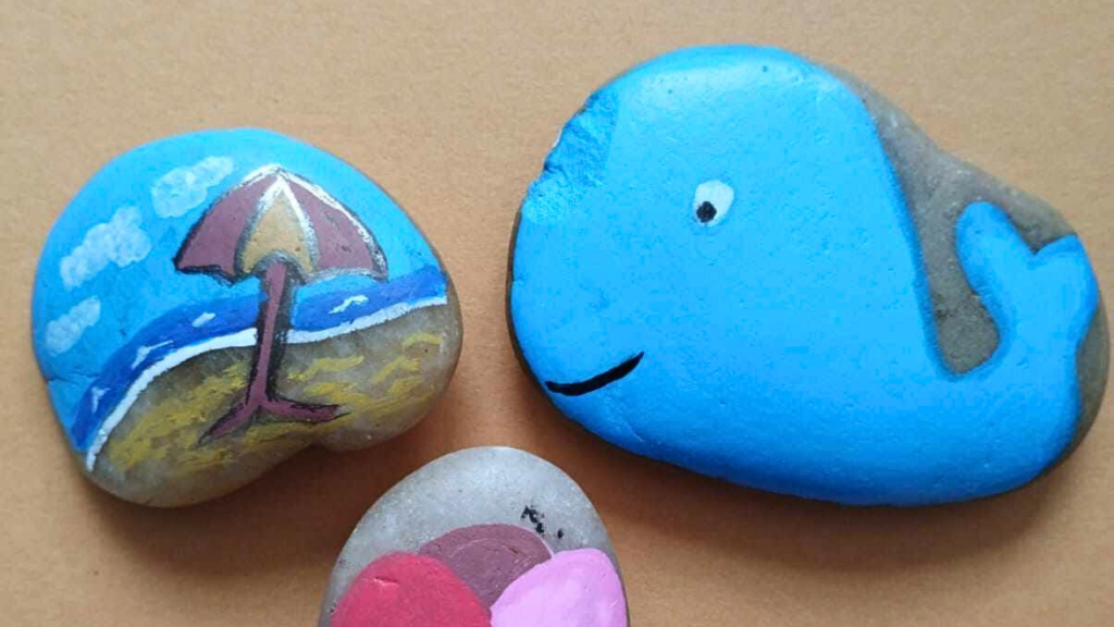 Pebbles painted to look like a beach scene and a whale