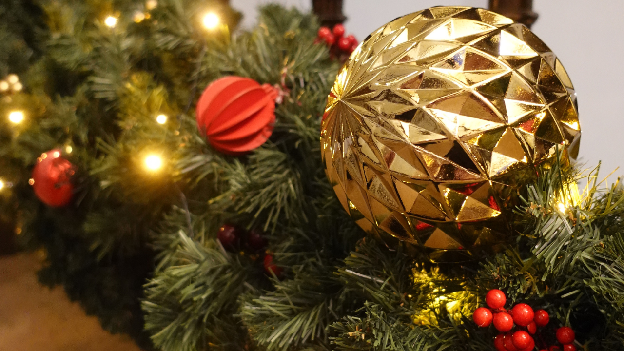 A gold bauble and red Christmas decorations on a staircase garland