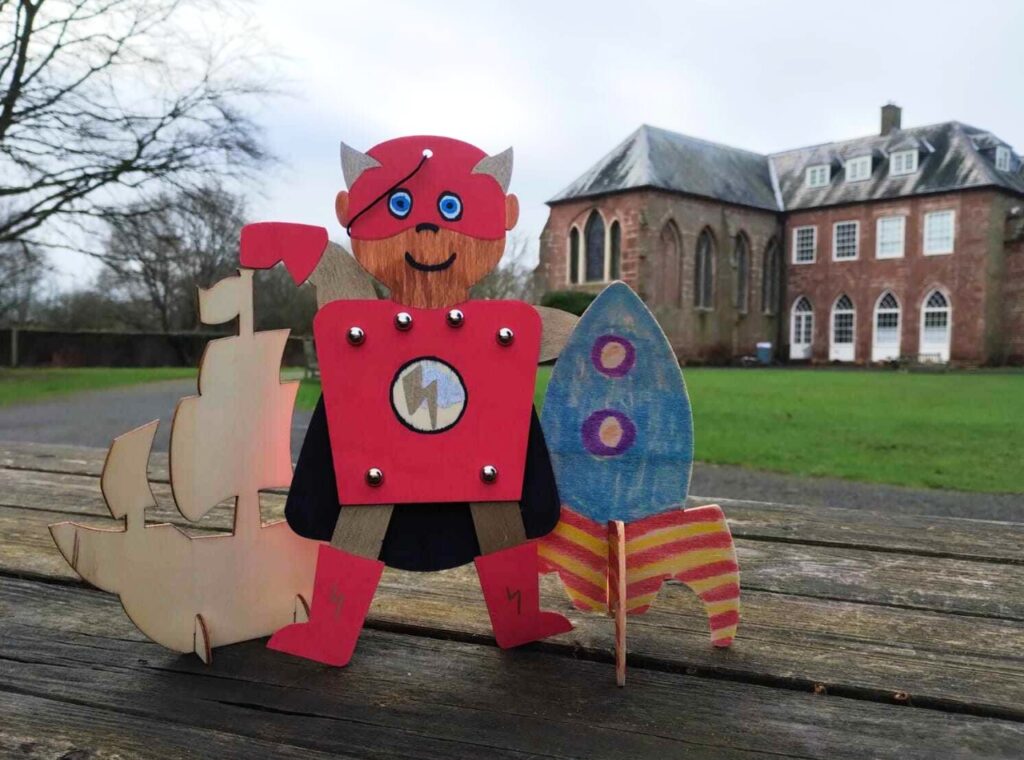 Crafts on a bench in front of Hartlebury Castle - a wooden ship, a superhero puppet and a rocket