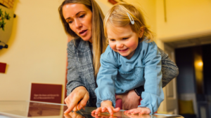 A mother and female child looking at something in a display case