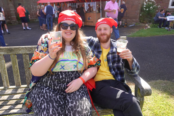 Man and woman wearing Chouffe hats and drinking beer on a Hartlebury Castle bench