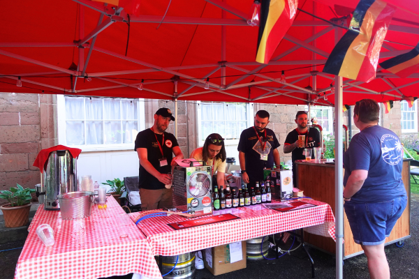 Four people serving behind the Chouffe and Belgian beer bar outside at Hartlebury Castle