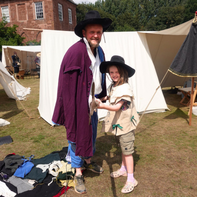 Man and young girl, dressed up in 17th century style clothes, hold a sword
