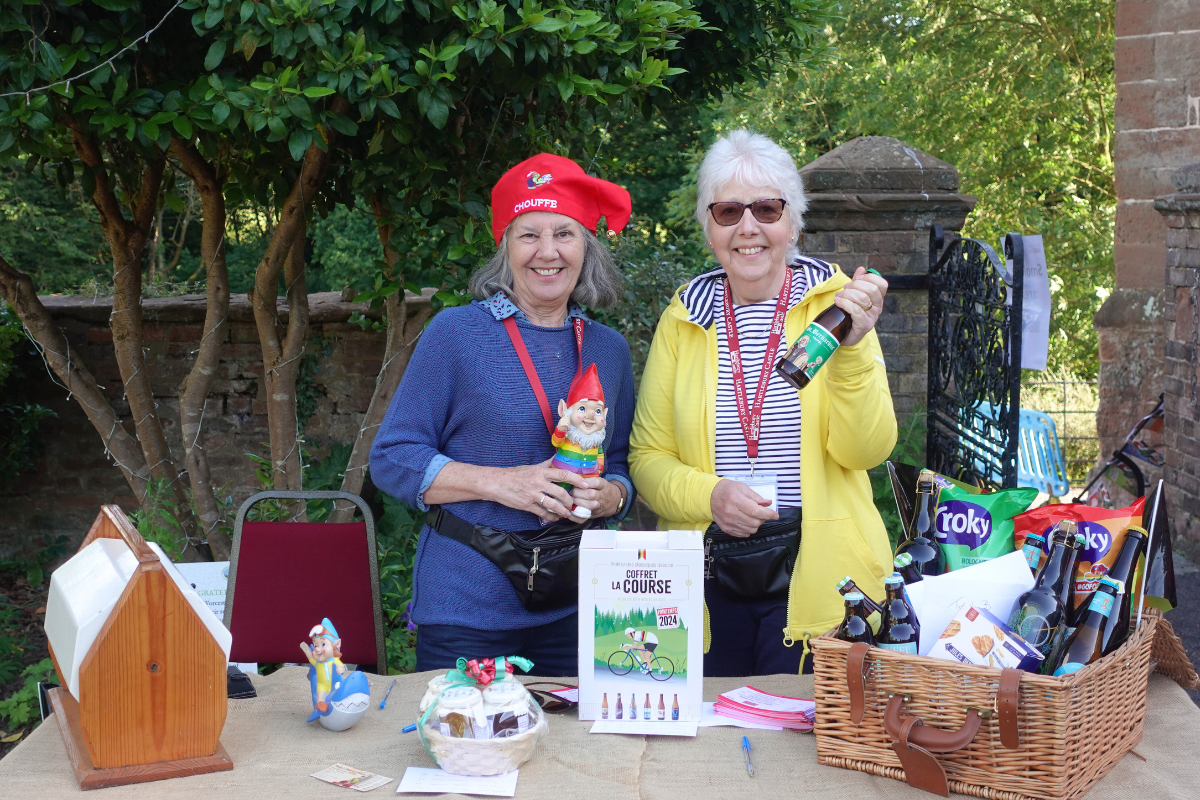 Two older women smile at a raffle and tombola stall outside at a Belgian themed event