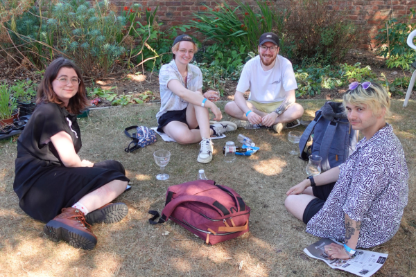 Four young people sitting on the grass enjoying beer