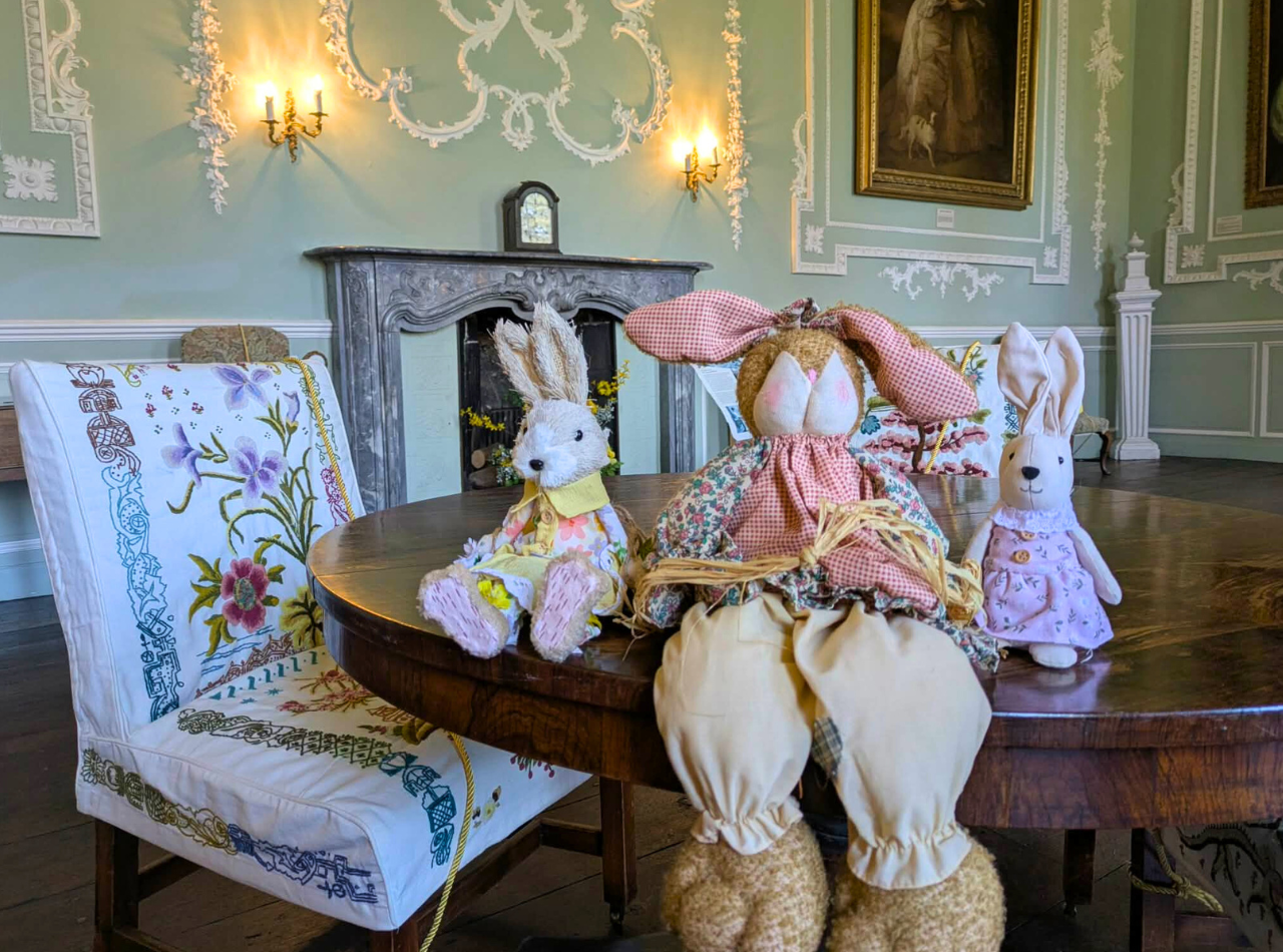 Three bunny toys in the Castle Saloon by an embroidered Carew chair
