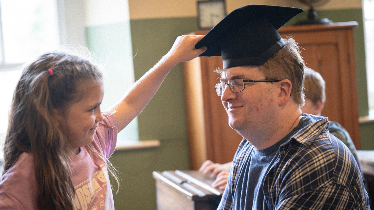 Girl placing a mortarboard on a man's head