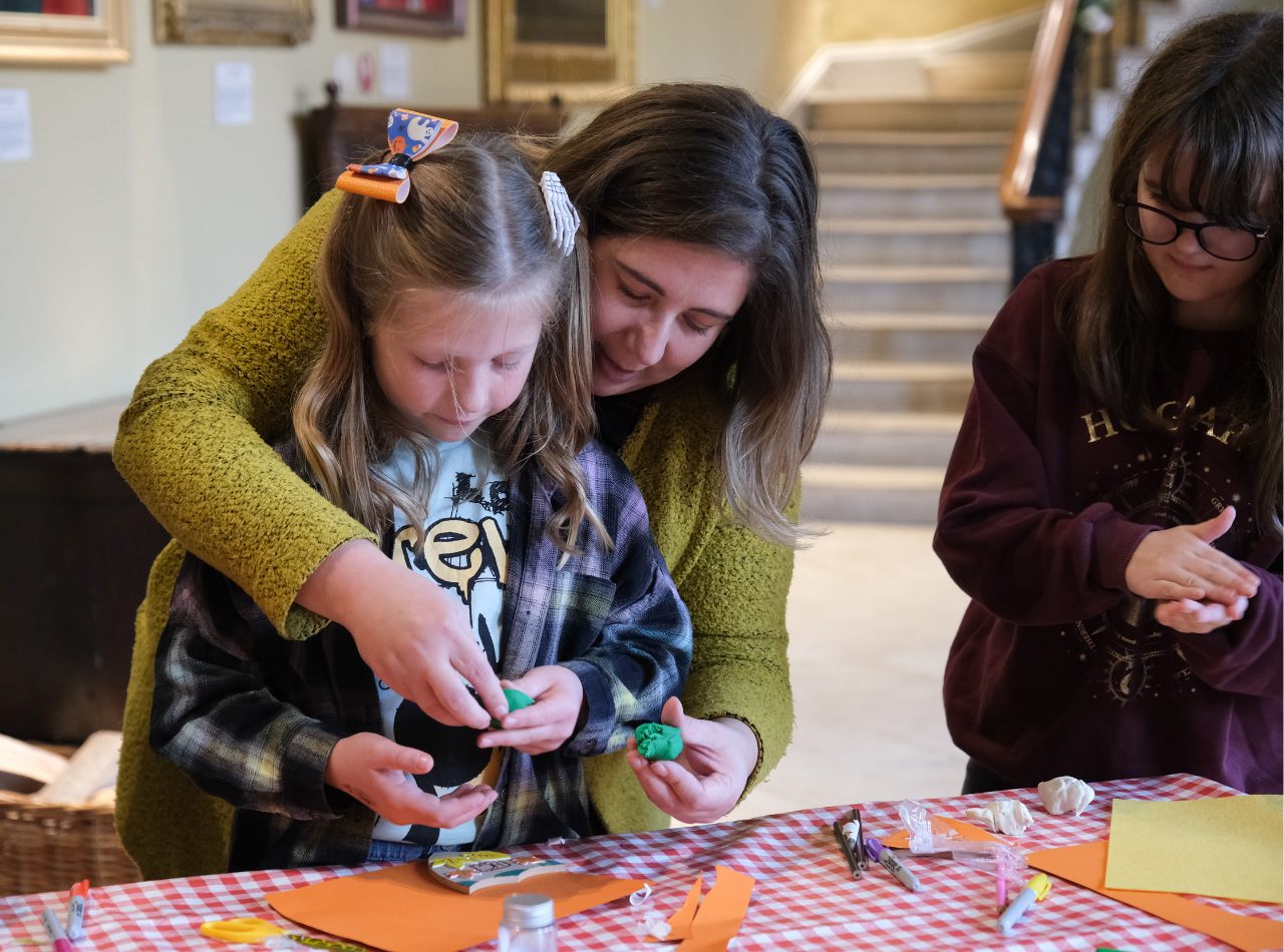 Woman helps two girls with paper crafts