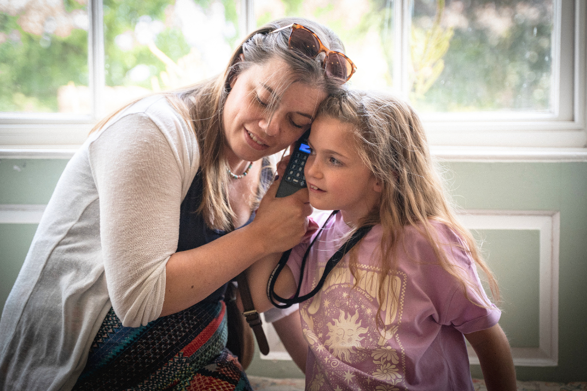 Woman and girl listening to an audio guide in front of a window