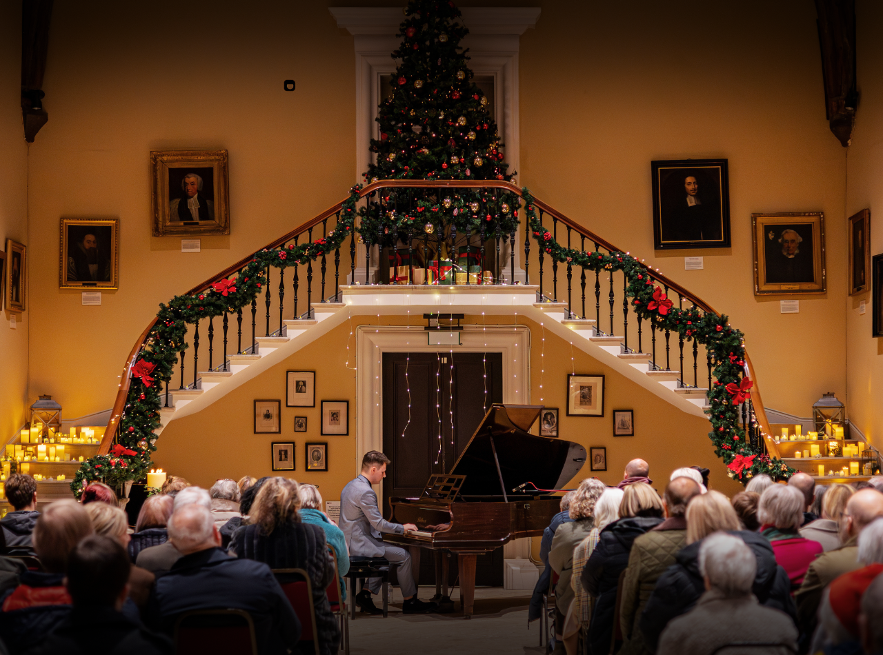 Daniel J Collins playing the piano for a concert audience in the Castle's festive Great Hall