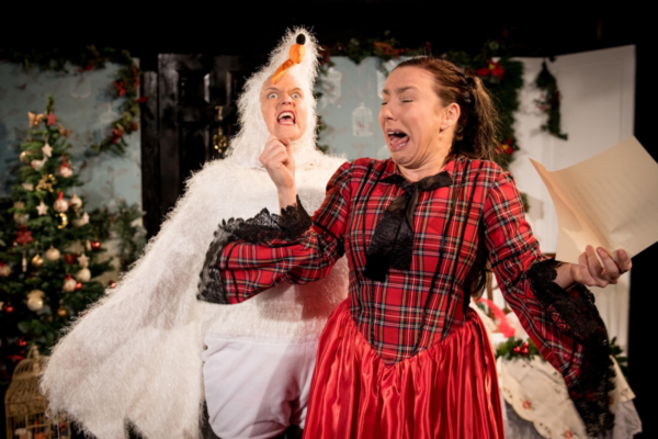 Two actors performing on a festive stage, portraying a bird scaring a woman